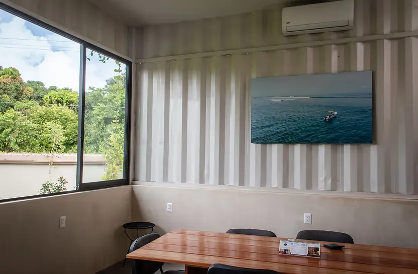 Local de la plaza con ventana al jardín, mesa de madera y una fotografía de surf en la pared.